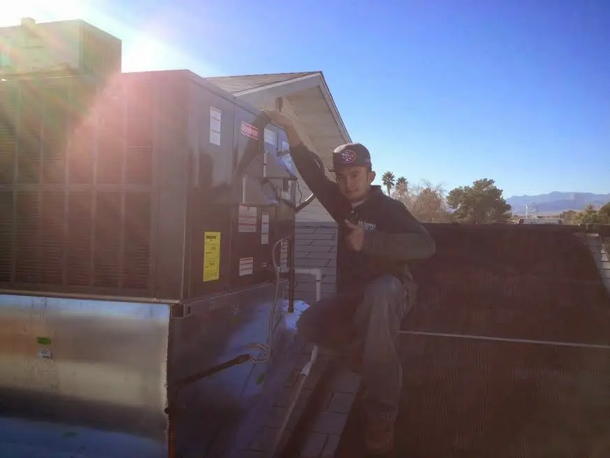 HVAC technician performing AC Tune-Up on a rooftop unit in Ashwaubenon